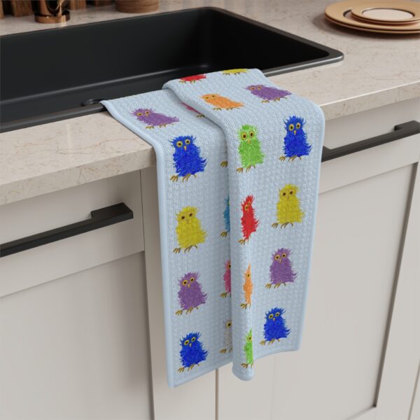 sky blue tea towel featuring Paul Myrick's colorful barn owls artwork - hanging on a kitchen sink