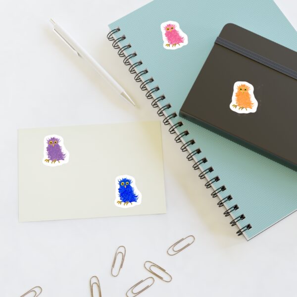 kiss-cut sticker sheet featuring 4 colorful barn owls by Paul Myrick, shown applied to a notebook